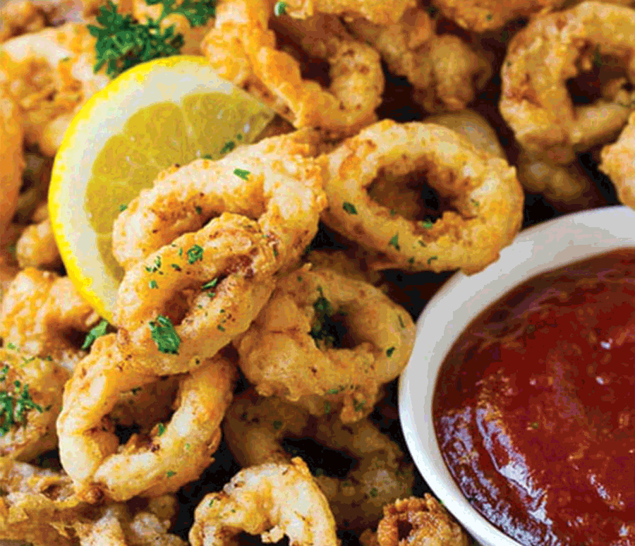 Actual item may vary from image shown Photo of calamari with lemon wedge and red dipping sauce.